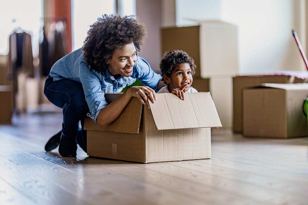 Mamá empujando a su hijo en una caja de mudanza