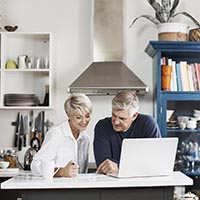 Shot of a mature couple using their laptop while bonding at home