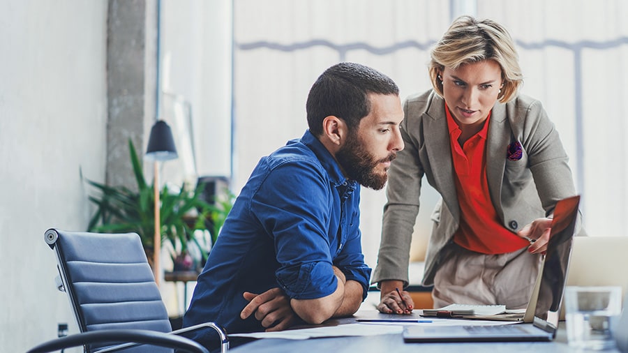 Man and woman who are office workers looking at a computer together.