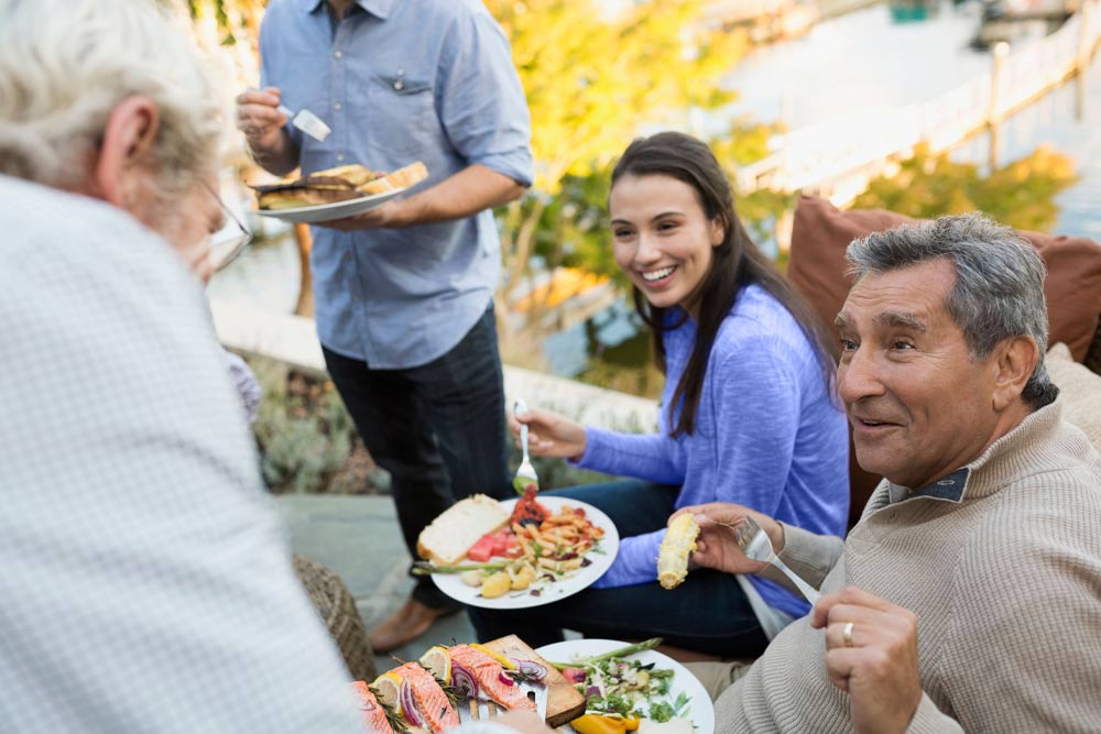 Photo of multi-generational family happily dining outdoors