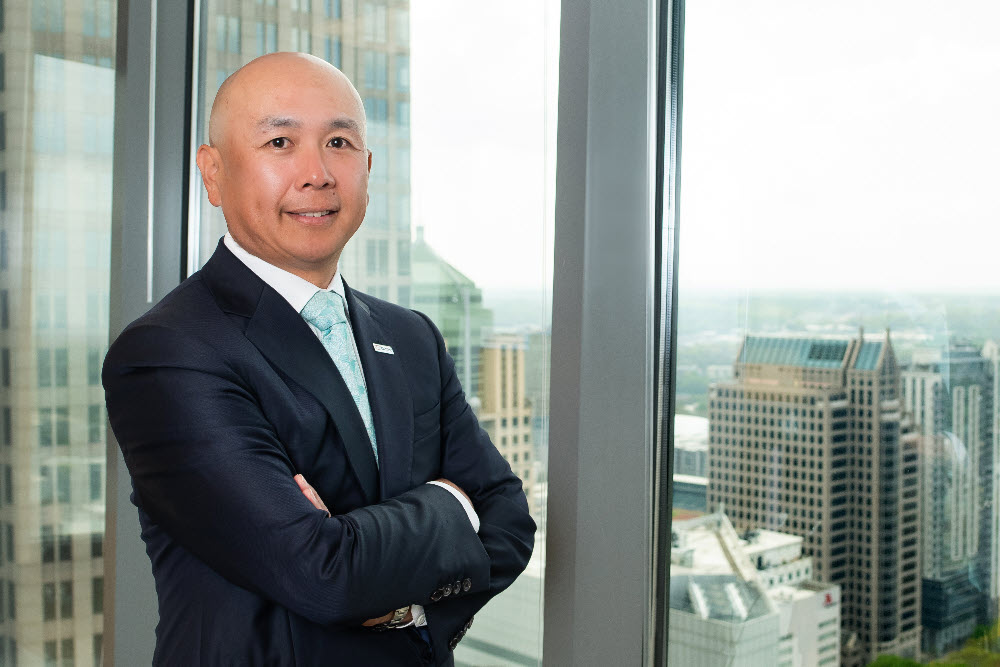 Headshot photo of Dan Son standing in front of downtown office buildings