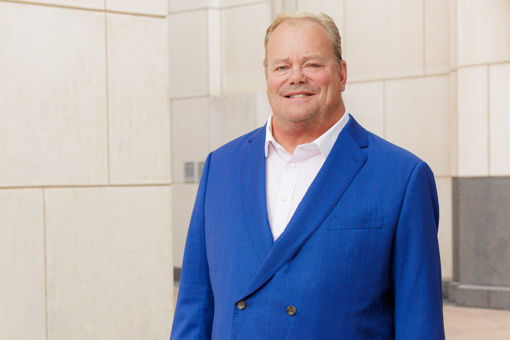 Man with blue suit coat posing in front of a building