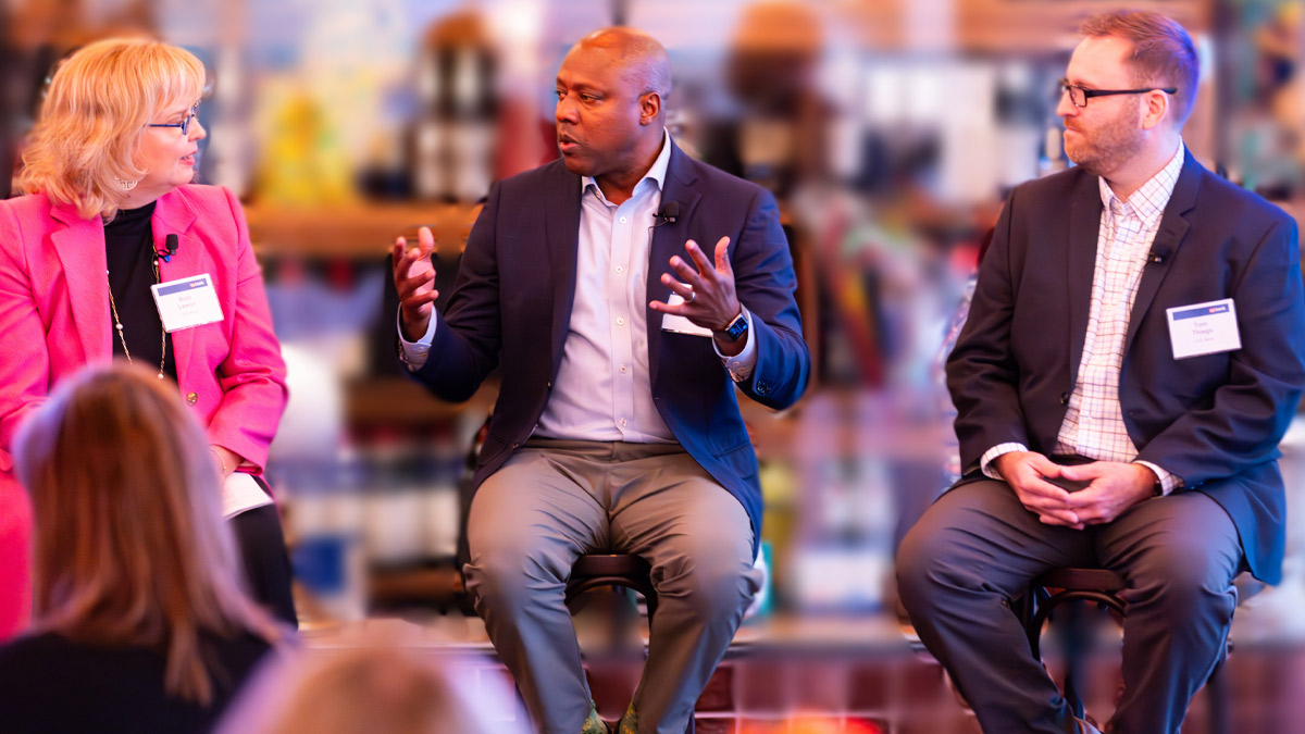 Photo of three people sitting in front of an audience at an event