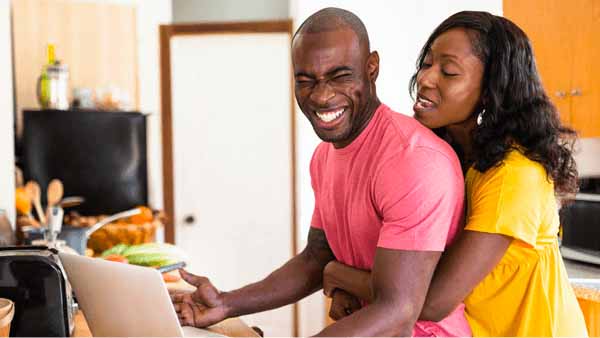 A smiling couple uses a laptop, exploring information related to mortgage points