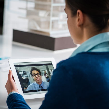 Woman holding a tablet and engaging in a virtual meeting with her investment advisor.