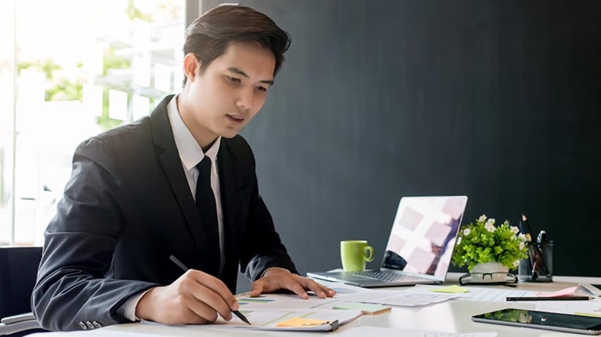 Man sitting at desk looking over paperwork about ASC 842 lease accounting standards.