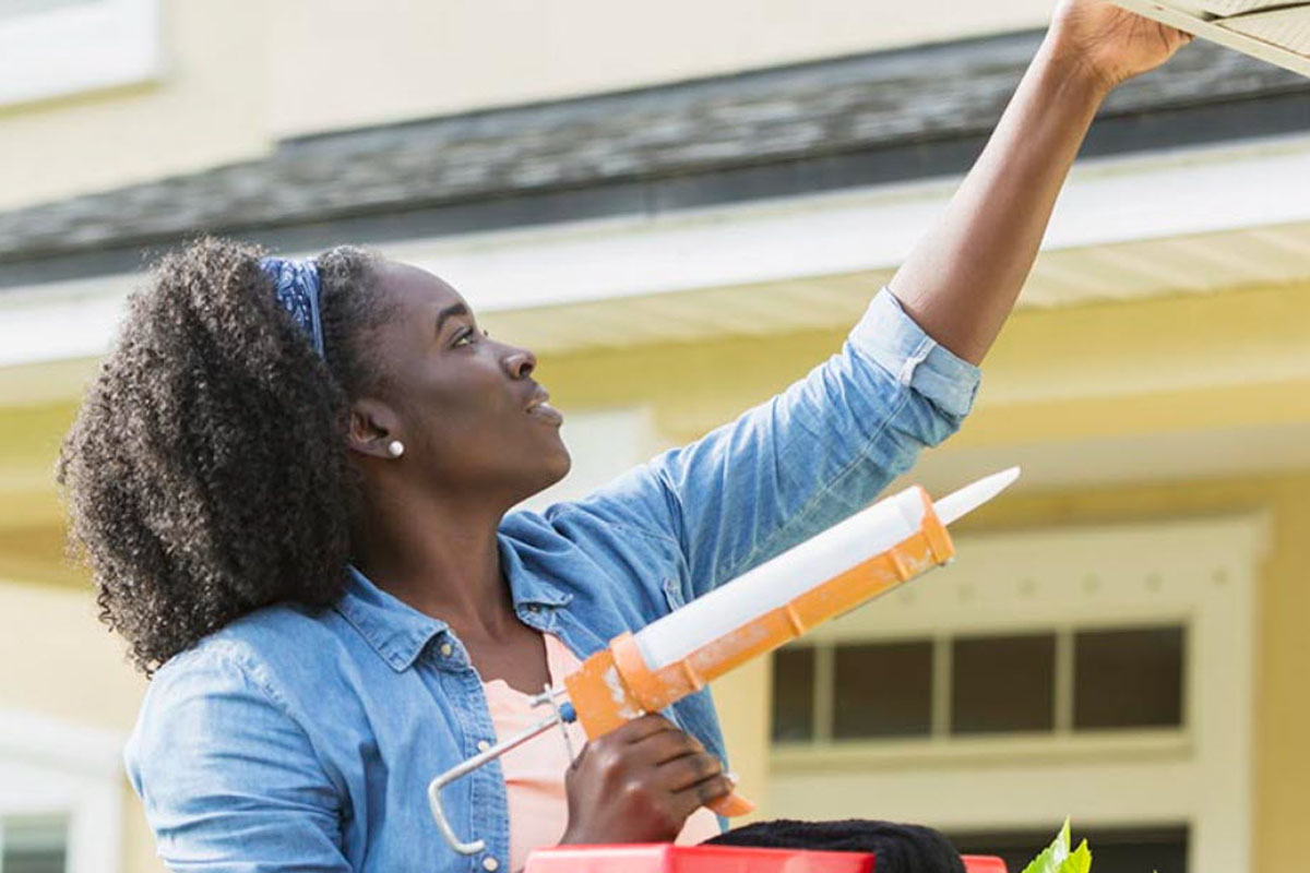 A woman on a ladder working on a home repair
