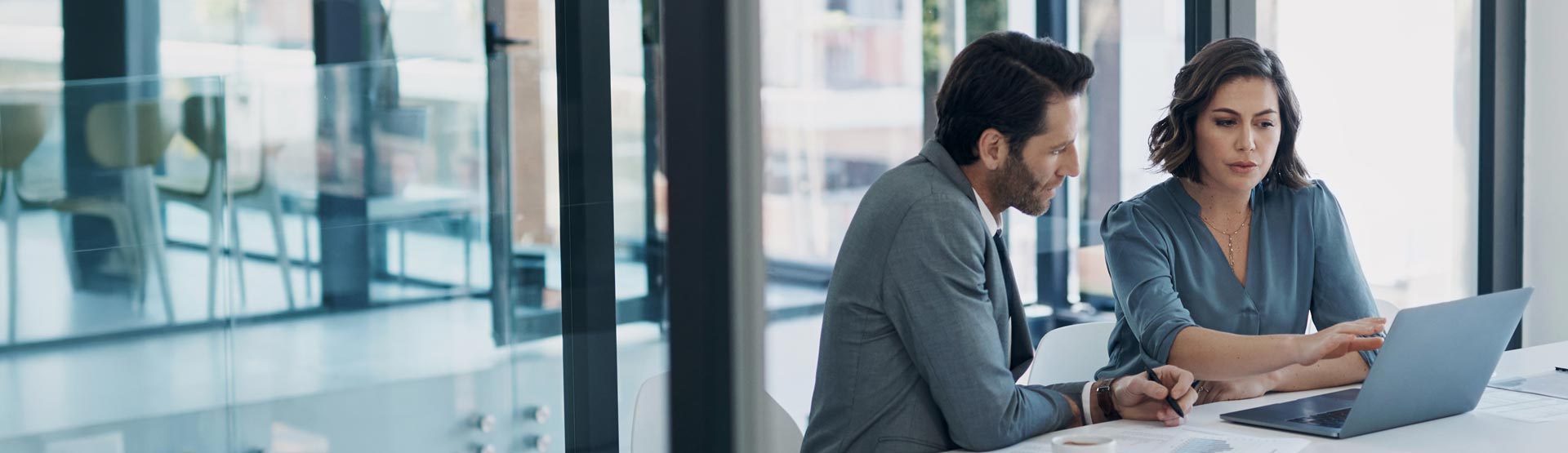 Professional man and woman looking at a laptop in a board room