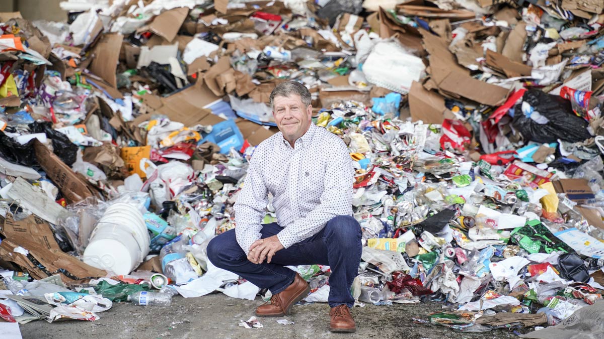 Man crouching in front of a heap of recyclable materials. 