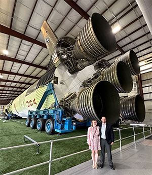 man and woman standing in front of Saturn V rocket ship