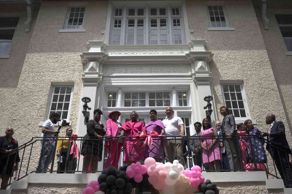 A group of Black community leaders standing on the steps of a public school that was re-opened as a community center thanks to tax credit financing