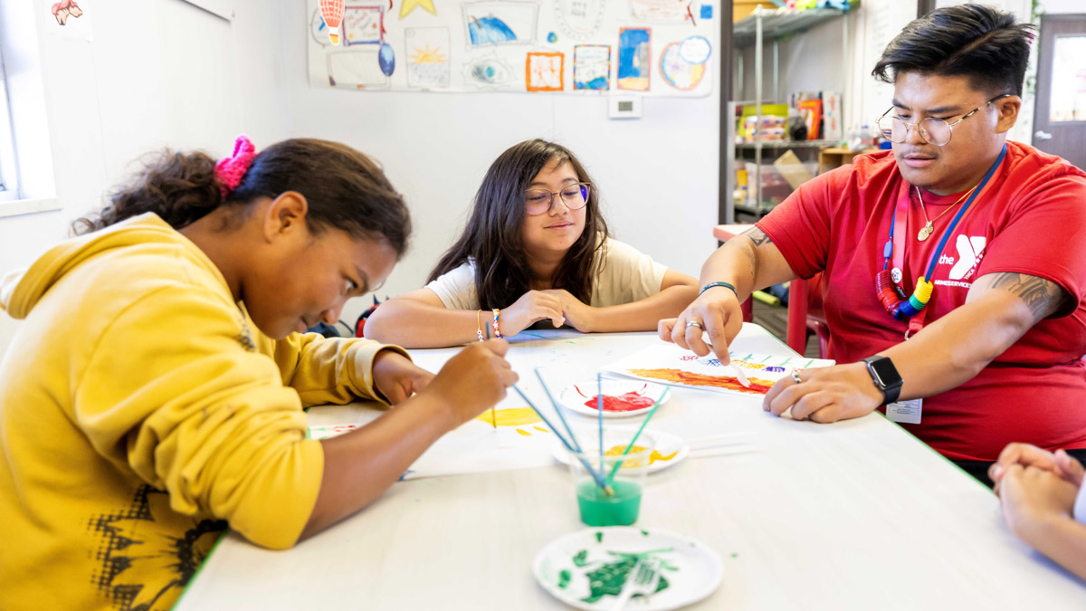 Man leading two children through an art project.