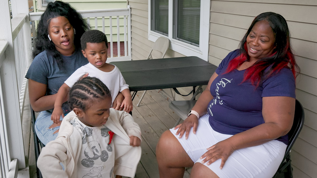 Woman with three children on front porch of home.