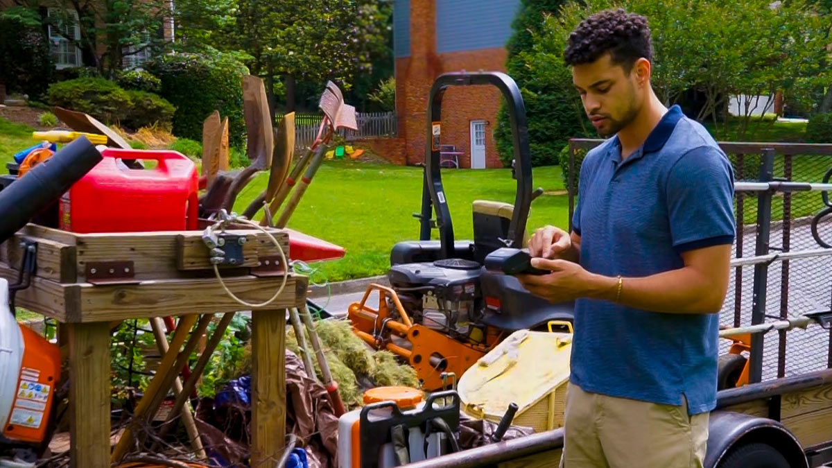 A man with landscaping equipment holding a payment terminal.