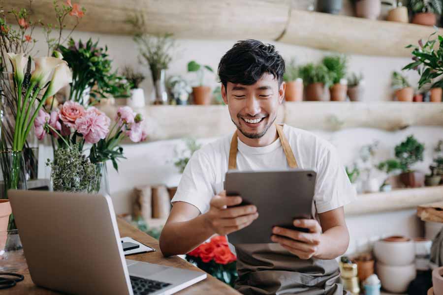 Owner of a flower shop researching busines money market accounts on his tablet.