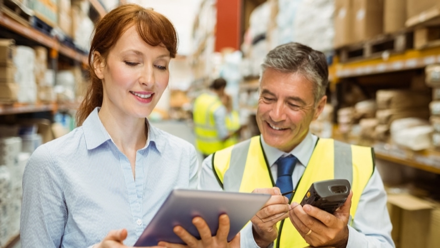 Two people standing in front of a stack of pallet boxes