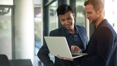 Two men working at laptop