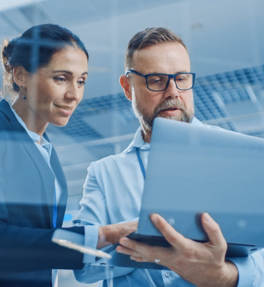 Man and woman standing and looking at a tablet device in their office