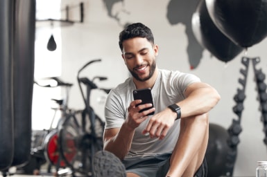 Persona utilizando un teléfono inteligente en el gimnasio