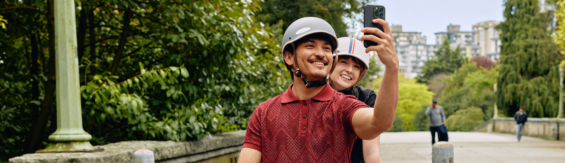 Joven pareja paseando fuera de la ciudad, usando cascos para bicicletas y tomándose una selfi.
