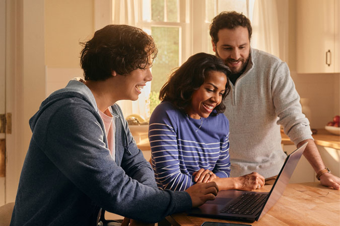Padre, madre e hijo mirando una laptop juntos.
