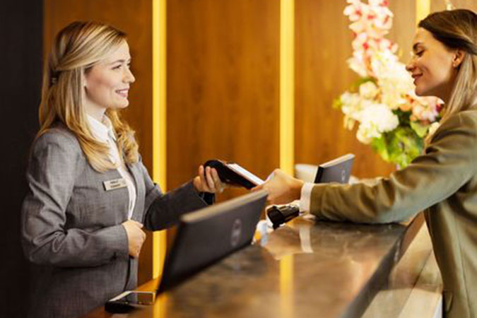 Hotel worker accepting a payment from a guest at the front desk.